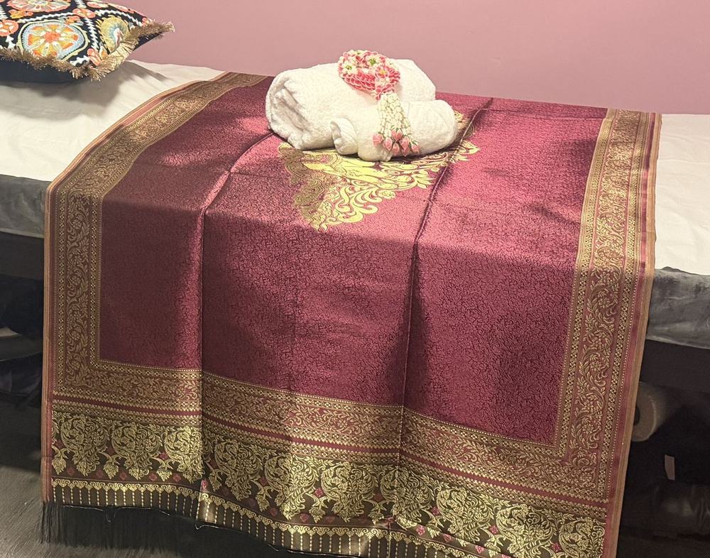 Rolled towel resting on red and gold Thai silk