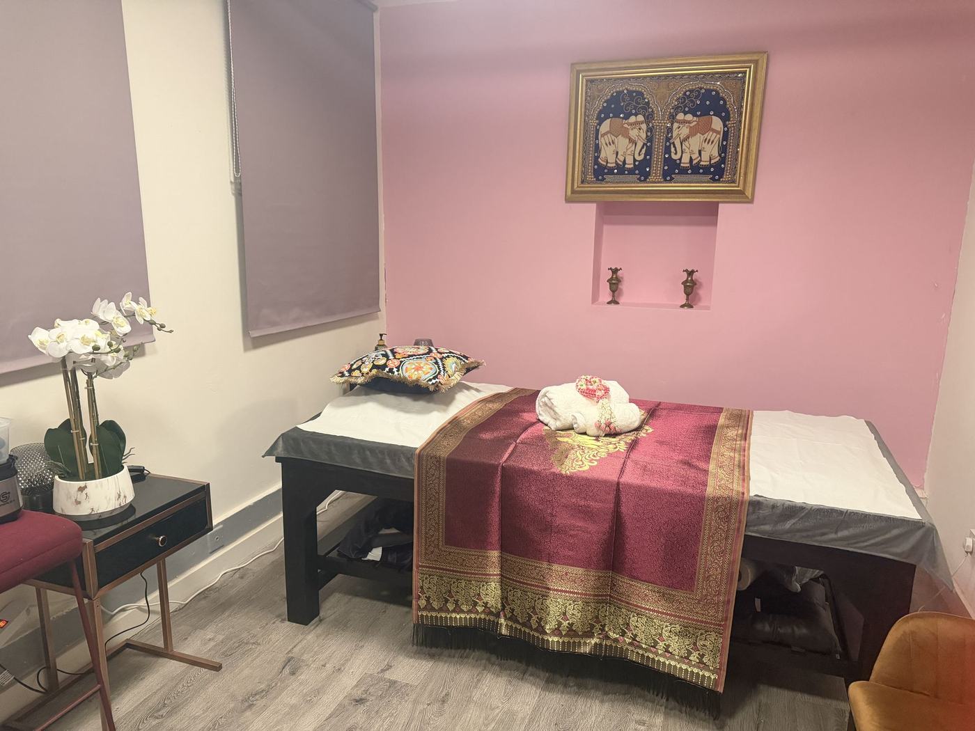 The treatment room with pink walls and a silk-dressed massage bed